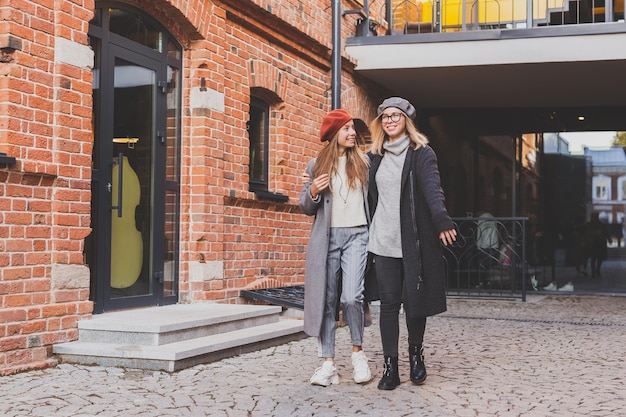 Deux filles marchant dans la rue ensemble, elles portent des vêtements de printemps ou d'automne et elles sont heureuses