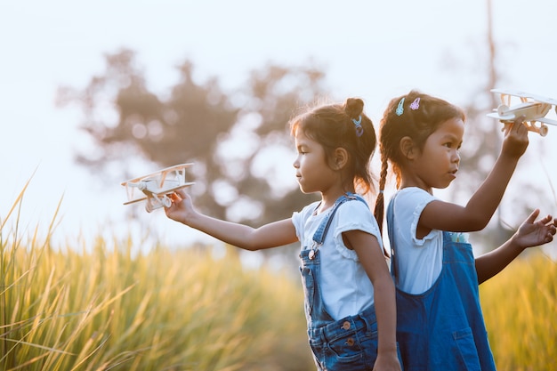 Deux filles mignonnes enfant asiatique jouant avec avion en bois jouet dans le champ