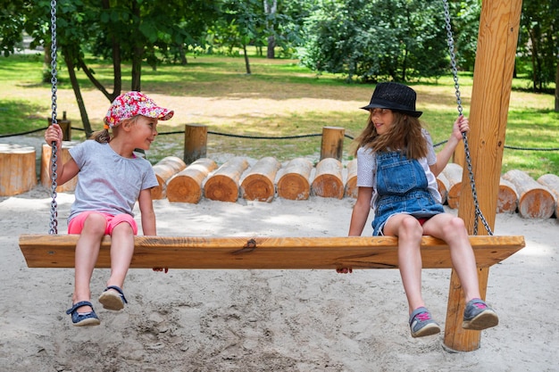 deux filles montent sur un banc - balançoire se regardant