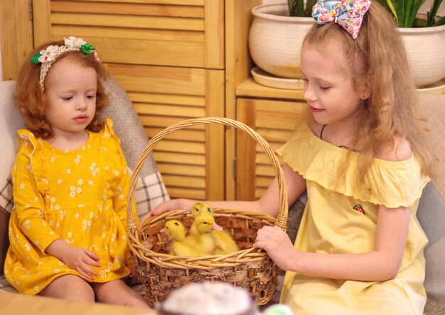 Deux filles à Pâques avec de petits canetons jaunes à côté du gâteau et des oeufs peints Bonheur de famille de vacances