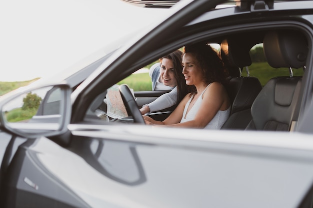 Deux filles parcourent les routes en voiture, regardent la carte. Concept de vacances