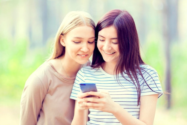 Deux filles regardent dans le téléphone pour une promenade dans la forêt d'été