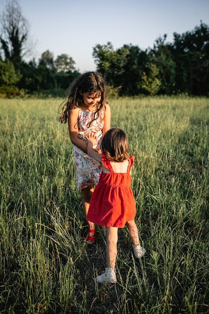 Deux filles en robe jouant l'une avec l'autre dans le champ du soir.