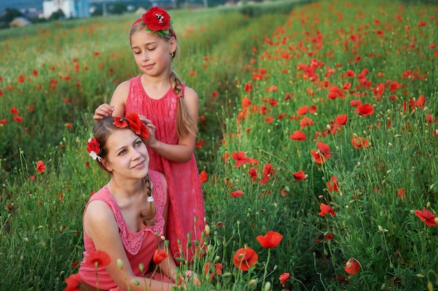 Deux filles en robe rouge marchant sur un champ de coquelicot