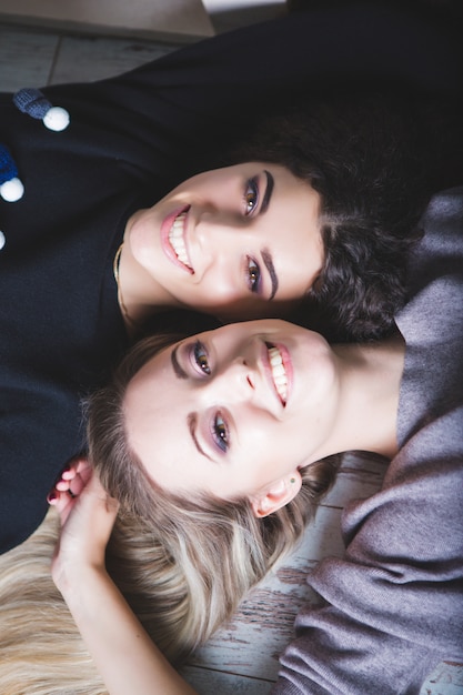 Deux filles s'allongent sur le lit et sourient.