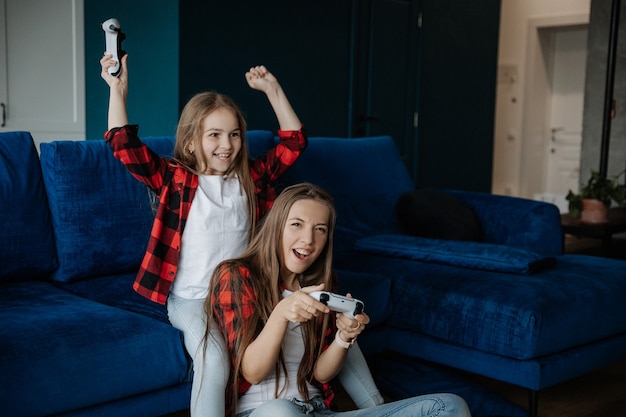 Deux filles s'amusent et jouent à une console avec un joystick jeune soeur gagne