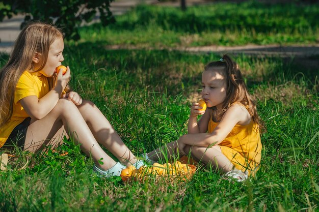 deux filles s'assoient par terre et mangent des abricots jaunes mûrs