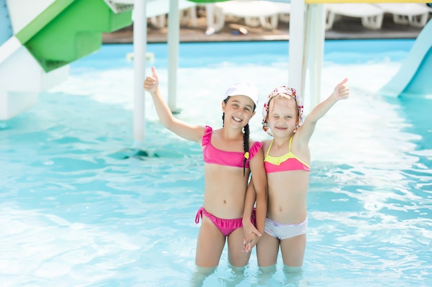 Deux filles s'éclaboussent dans une piscine extérieure en été. Enfants heureux, soeur jouant, profitant du temps ensoleillé dans la piscine publique.