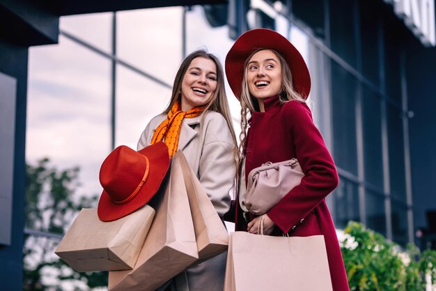 Deux filles avec des sacs à provisions devant la vitrine