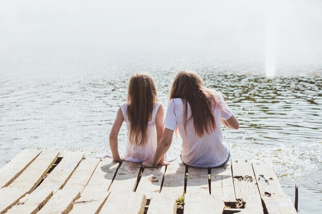 Deux filles se détendent au bord de la rivière sous les rayons du soleil. Photos avec points culminants