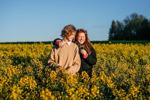 Deux filles se tiennent dans un champ de colza au printemps et regardent le soleil