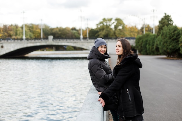 Deux filles se tiennent sur le talus près de l'eau et regardent dans le cadre. Photo de haute qualité