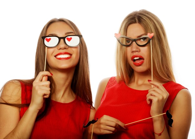 Deux filles sexy élégantes meilleures amies vêtues d'une robe rouge prête pour la fête, sur fond blanc