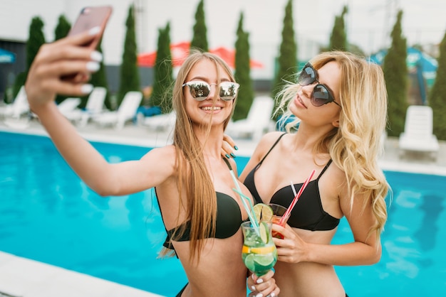 Deux filles sexy font un selfie près de la piscine