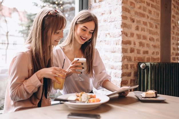 Deux filles shopping sur une tablette dans un café