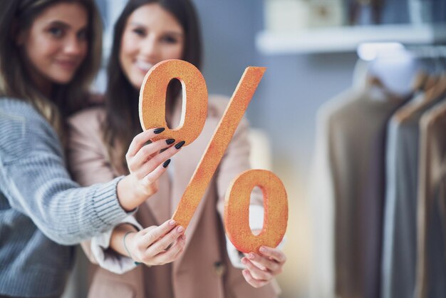 Deux filles sur shopping tenant un signe de pourcentage de vente. photo de haute qualité