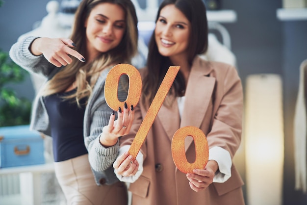 Deux filles sur shopping tenant un signe de pourcentage de vente. photo de haute qualité