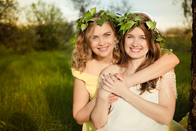 Deux filles souriant et étreignant à l'extérieur en été