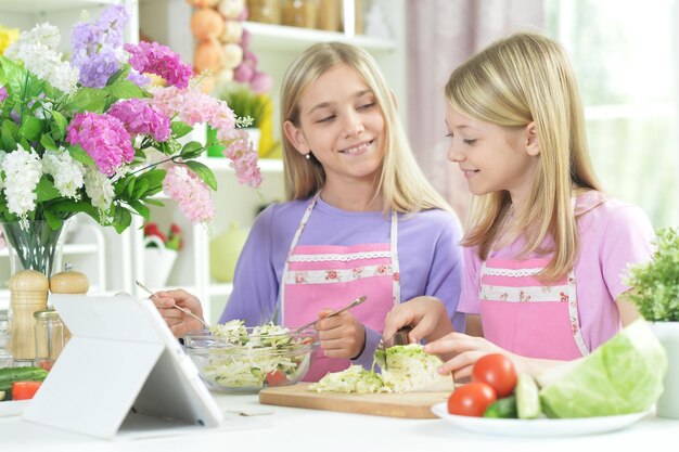 Deux filles en tabliers roses préparant une salade fraîche