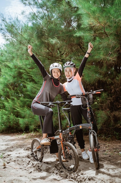 Deux filles voilées avec les poings serrés tout en faisant du vélo ensemble