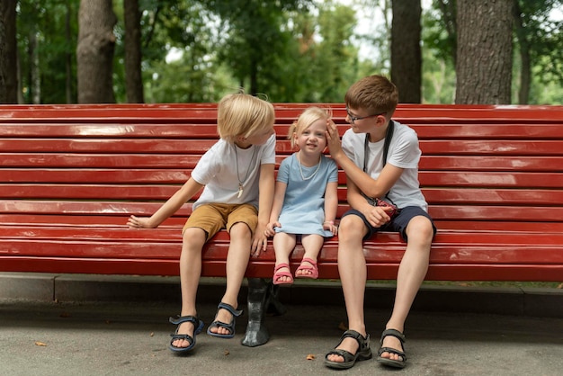 Deux frères aînés et petite sœur se détendent dans le parc le jour d'été