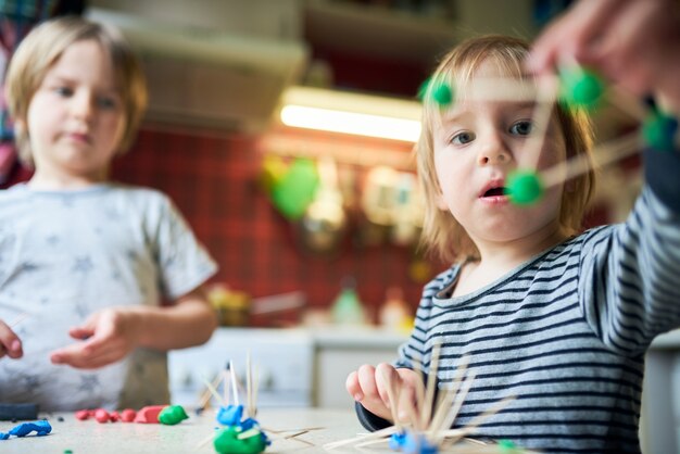 Deux frères font des figures tridimensionnelles de pâte à modeler et de bâtons