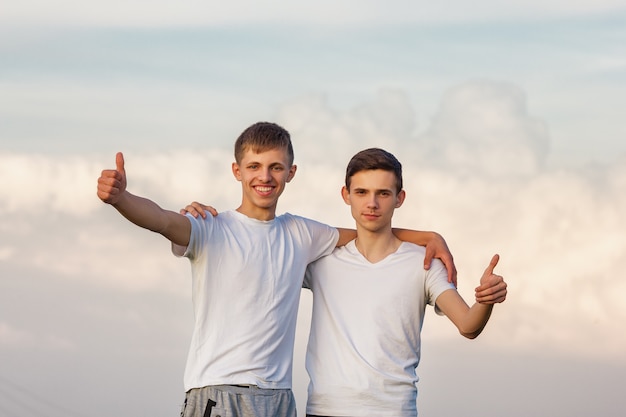 Deux frères frères sont heureux contre le ciel.