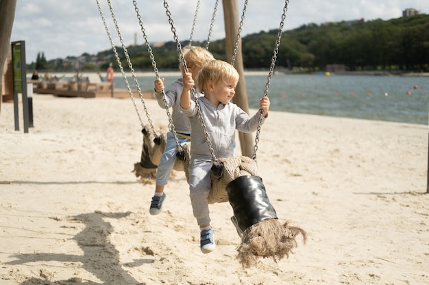 Deux frères jumeaux enfants garçons jouant sur une aire de jeux pour enfants dans une journée ensoleillée d'automne.