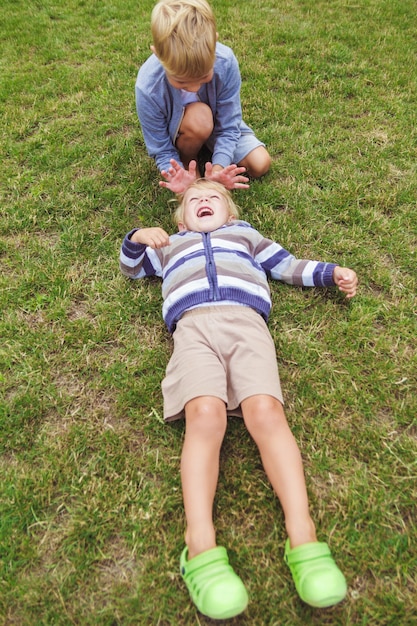 Deux frères s'amusent à jouer sur la pelouse verte.
