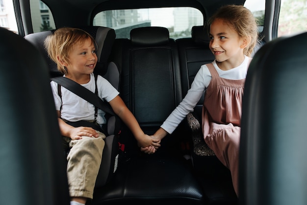 Deux frères et sœurs aimants assis sur le siège arrière d'une voiture, se tenant la main, se regardant. Montrer son soutien.