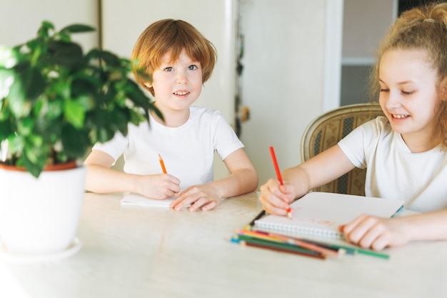 Deux frères et sœurs frère et sœur bambin garçon entre fille dessin sur table dans la cuisine à la maison