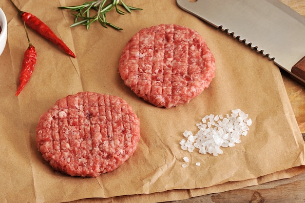 Deux galettes crues de viande hachée sous la forme d'un cercle et un couteau machette à papier