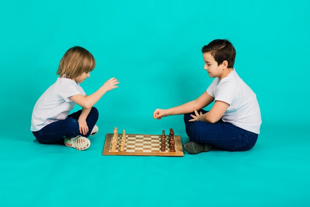 Photo deux garçon sérieux jouant aux échecs dans , fond bleu