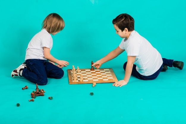 Photo deux garçon sérieux jouant aux échecs en studio, fond bleu