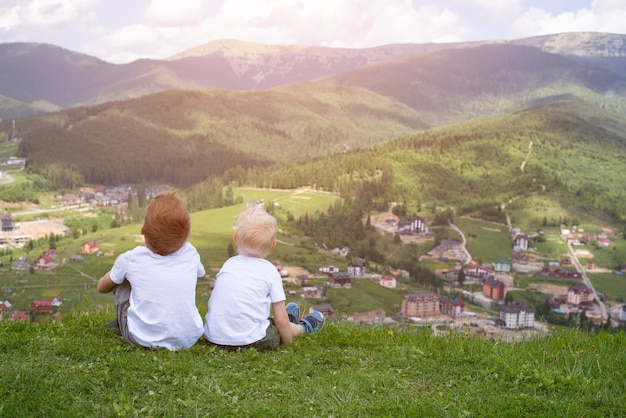 Deux garçons assis sur une colline et regardant les montagnes. Vue arrière