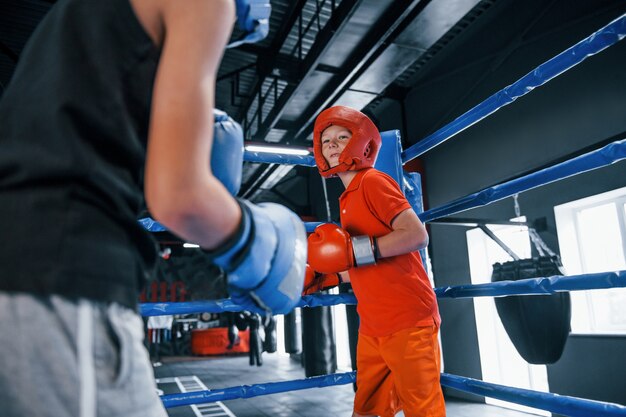 Deux garçons en équipement de protection s'entraînent et se battent sur le ring de boxe.