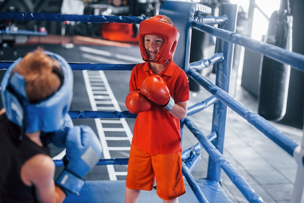 Deux garçons en équipement de protection s'entraînent et se battent sur le ring de boxe.