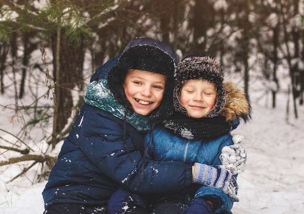 Deux garçons en hiver dans la nature câlins. Deux frères s'amusent à l'extérieur