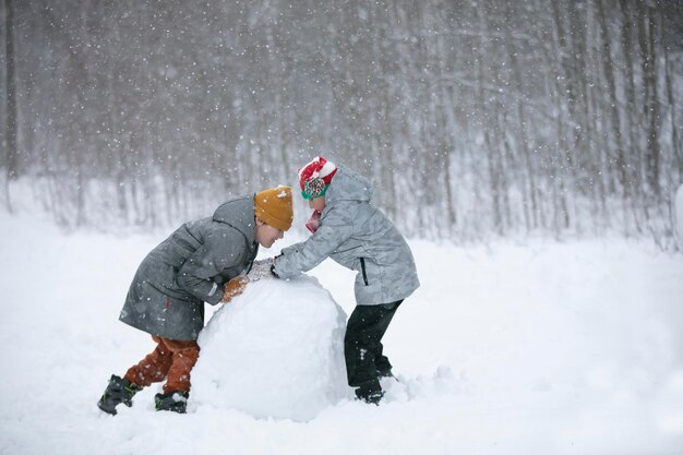 Deux garçons jouent dans la neige Les enfants sculptent dans la neige Jouez un jour d'hiver dans la nature