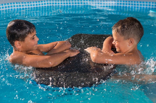 Deux garçons jouent dans la piscine beaucoup d'éclaboussures et de gouttes d'eau une enfance heureuse