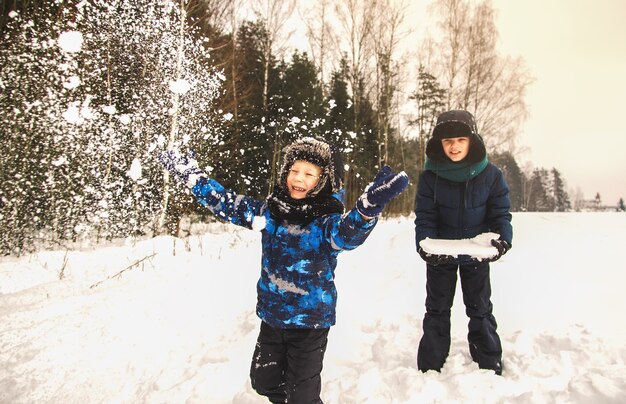 Deux garçons jouent avec la neige dans le parc en hiver. Frères en promenade