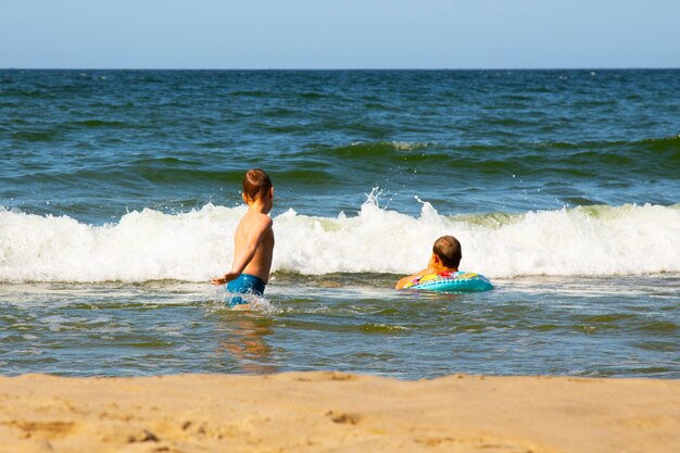 Deux garçons nageurs dans l'eau. Deux frères jouant dans la mer. sauter sur les vagues. une enfance amusante en mer. Vacances sous les tropiques. Les garçons jouent dans l'océan.