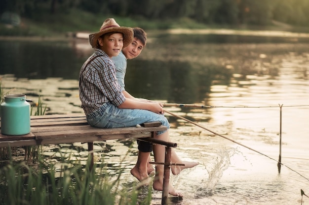 Deux garçons pêchent sur le lac du village au coucher du soleil en été