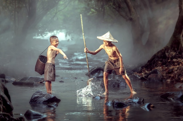 Photo deux garçons s'amusent joyeusement. attraper du poisson dans les ruisseaux. et c’est le mode de vie des enfants du nord-est de la thaïlande.