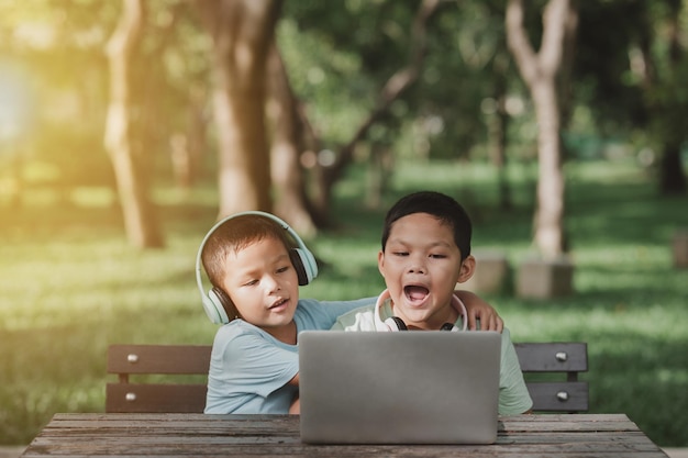 Deux garçons sont assis dans leur jardin. Les enfants jouent joyeusement à des jeux informatiques.