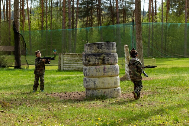 Deux garçons vêtus de camouflage jouant au laser tag dans une aire de jeux forestière spéciale