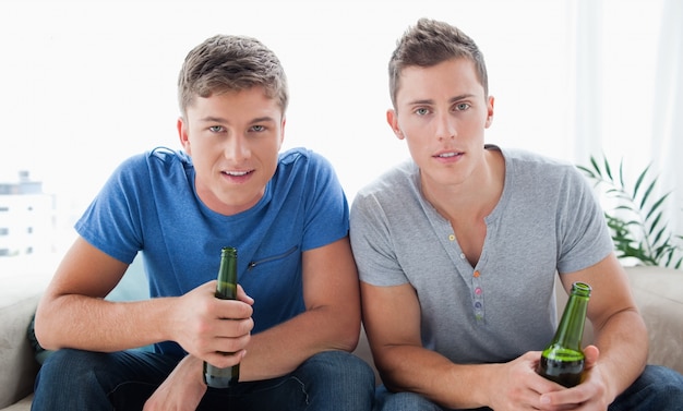 Deux gars regardant dans la caméra avec de la bière à la main