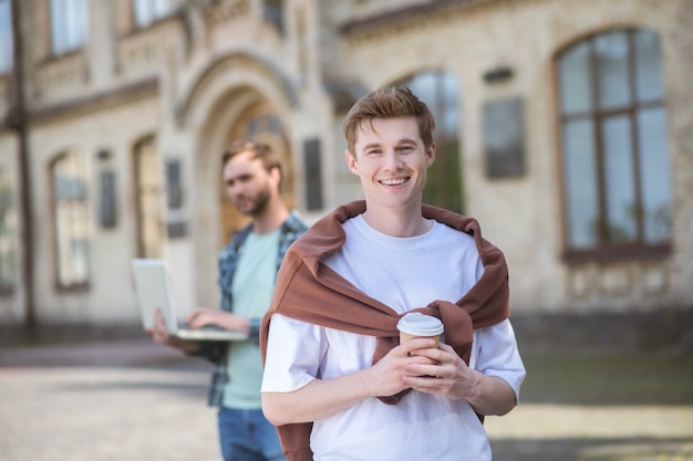 Deux gars souriants dans une cour d'université semblant joyeux