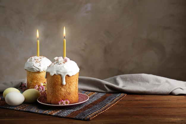 Deux gâteaux de Pâques avec des bougies allumées sur une table en bois