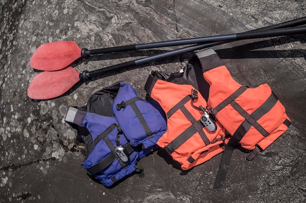 Photo deux gilets de sauvetage et une radio se trouvent sur la côte rocheuse près des rames de mensonge